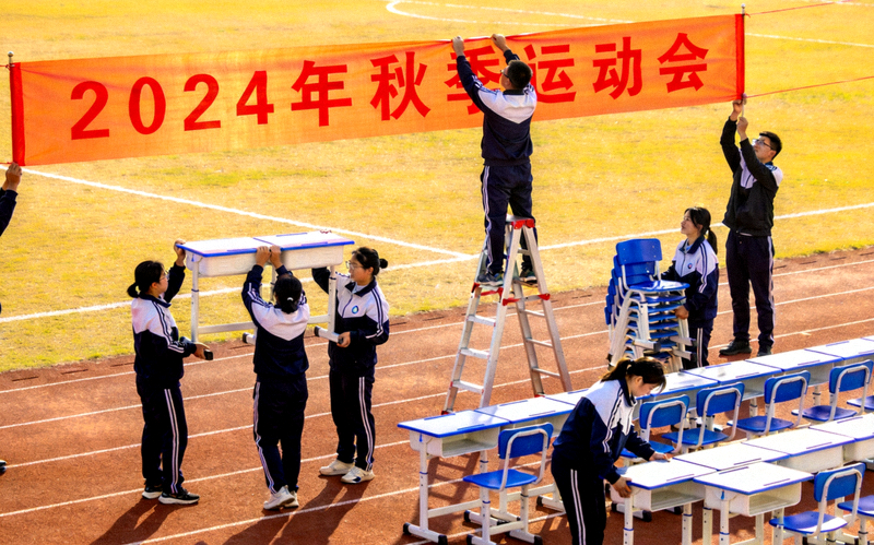 工作人员正在布置运动会场地 - 摆放桌椅和悬挂横幅