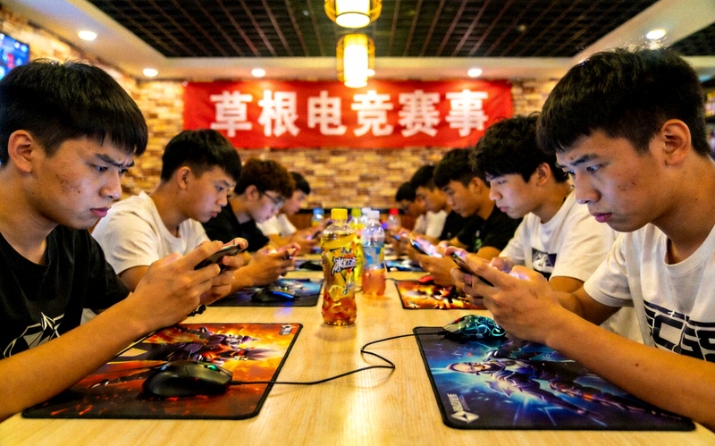 社区网吧内举办的草根电竞赛事 - 年轻选手们全神贯注进行手机游戏对战