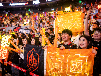 PEL比赛现场观众席座无虚席，粉丝们挥舞着战队应援物，气氛热烈